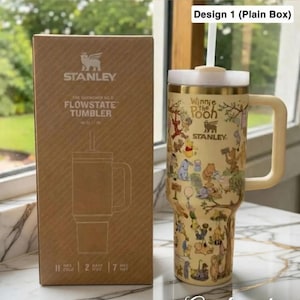 Puede incluir: Un vaso Stanley Flowstate beige con un dise&ntilde;o de Winnie the Pooh, un asa y una pajita. Junto a &eacute;l, una caja marr&oacute;n con el logotipo de Stanley y los detalles del producto. El vaso mantiene las bebidas fr&iacute;as durante 11 horas.