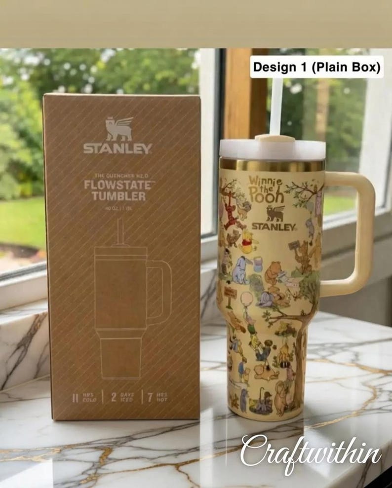 Puede incluir: Un vaso Stanley Flowstate beige con un dise&ntilde;o de Winnie the Pooh, un asa y una pajita. Junto a &eacute;l, una caja marr&oacute;n con el logotipo de Stanley y los detalles del producto. El vaso mantiene las bebidas fr&iacute;as durante 11 horas.