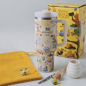 Puede incluir: Un termo de viaje Stanley con ilustraciones de Winnie the Pooh, con tapa y asa blancas. Tambi&eacute;n hay una caja de regalo amarilla, una bolsa con cord&oacute;n y accesorios con tem&aacute;tica de abejas. La taza est&aacute; cubierta con ilustraciones de Pooh y sus amigos.