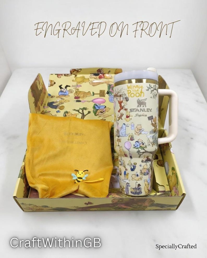 Puede incluir: Un juego de regalo tem&aacute;tico de Winnie the Pooh. El juego incluye un vaso Stanley con un asa blanca, una bolsa de terciopelo amarillo y una caja decorativa. El vaso est&aacute; cubierto de ilustraciones de los personajes de Winnie the Pooh. La caja y la bolsa son amarillas.