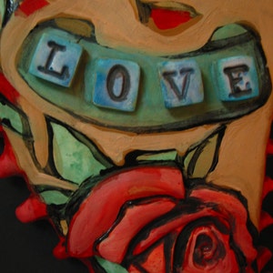 K&ouml;nnte beinhalten: Eine herzf&ouml;rmige Keramikskulptur mit einer roten Rose und dem Wort "LOVE" in blauen Fliesen.