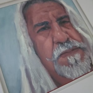 May include: A framed portrait painting of an older man with a white beard and mustache, wearing a white head covering. The painting is in a square white frame, with the artist's signature in the bottom left corner. The man's skin tone is a reddish-brown.