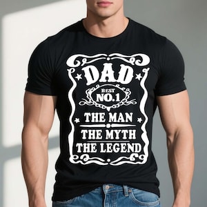 Pode incluir: Camiseta preta com um design gr&aacute;fico branco que diz "Dad - Best No. 1 - The Man The Myth The Legend".