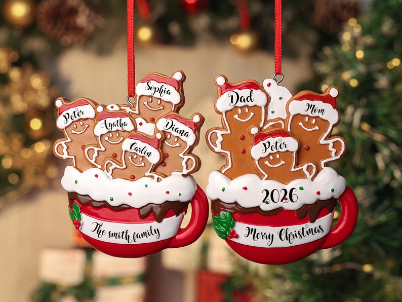 May include: Two hanging Christmas ornaments shaped like red mugs filled with gingerbread figures wearing Santa hats. The left mug features the names Peter, Agatha, Sophia, Carlin, and Diana with The Smith Family text. The right mug features Dad, Mom, and Peter with 2026 and Merry Christmas text.
