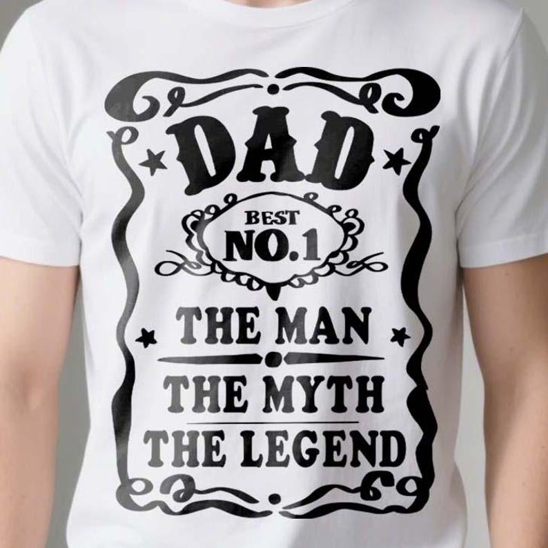 Pode incluir: Camiseta branca com um design gr&aacute;fico preto que diz "Dad Best No. 1 The Man The Myth The Legend".