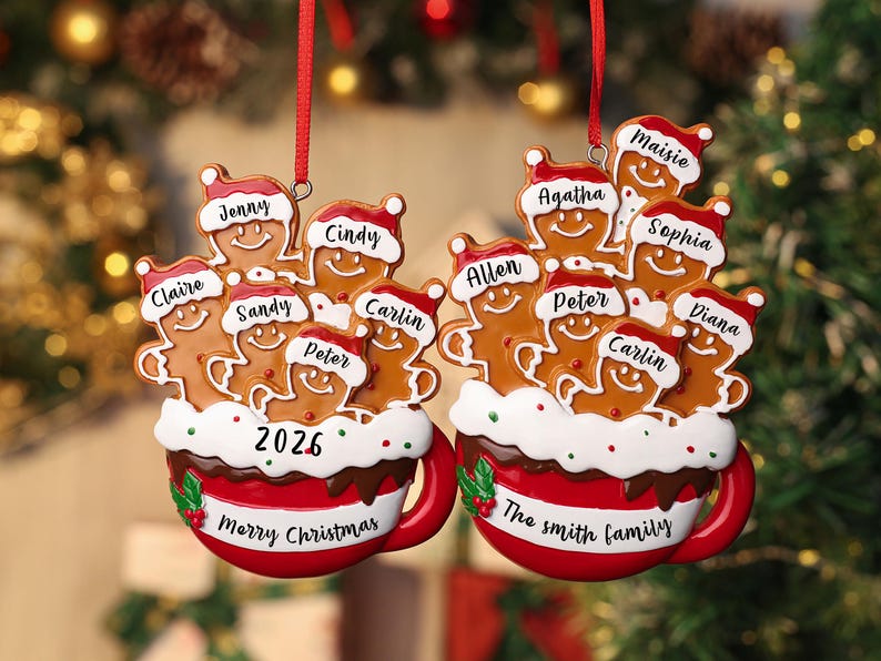 May include: Two red and white ceramic mug ornaments featuring gingerbread figures wearing Santa hats. The left mug displays the year 2026 and names Jenny, Cindy, Claire, Sandy, Peter, and Carlin. The right mug says The Smith Family with names Agatha, Maisie, Sophia, Allen, Peter, Carlin, and Diana.