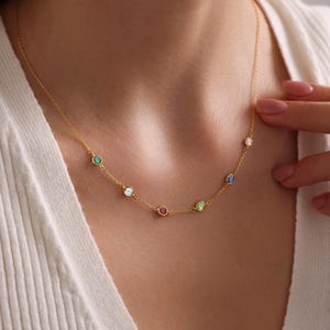 Op de afbeelding: Een gouden ketting met kleine gekleurde edelstenen. De ketting heeft een groene, witte, rode, groene en blauwe edelsteen.