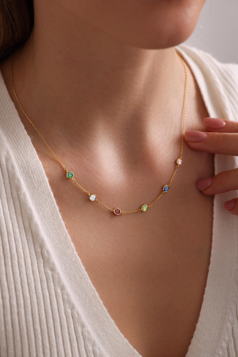 Op de afbeelding: Een gouden ketting met kleine gekleurde edelstenen. De ketting heeft een groene, witte, rode, groene en blauwe edelsteen.