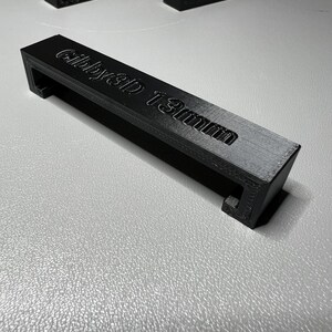 Puede incluir: Manija de pl&aacute;stico negro con el texto "Gibby3D 13mm" impreso en ella.