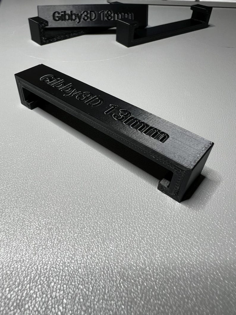 Puede incluir: Manija de pl&aacute;stico negro con el texto "Gibby3D 13mm" impreso en ella.