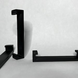 Puede incluir: Tres soportes de estanter&iacute;a de pl&aacute;stico negro. Los soportes tienen forma de L y tienen un borde en la parte superior e inferior para sujetar una estanter&iacute;a.