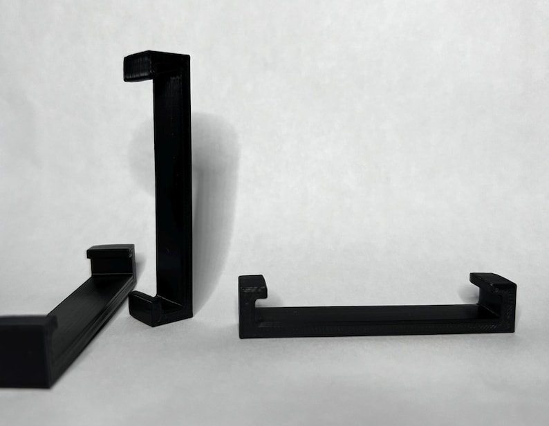 Puede incluir: Tres soportes de estanter&iacute;a de pl&aacute;stico negro. Los soportes tienen forma de L y tienen un borde en la parte superior e inferior para sujetar una estanter&iacute;a.