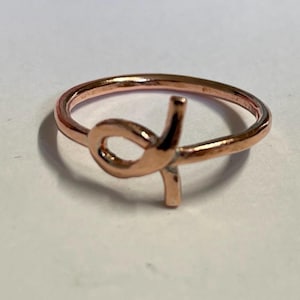 May include: A rose gold ring with a knot design.