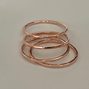 Peut inclure: Quatre bagues empilables martelées en or rose. Les bagues sont fines et délicates, et elles sont empilées les unes sur les autres.