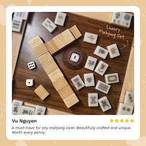 Puede incluir: Un lujoso juego de Mahjong con fichas de madera y un tablero de juego de madera. El juego incluye dados y un soporte de fichas de madera. Las fichas tienen varios s&iacute;mbolos y caracteres. El texto "Luxury Mahjong Set" es visible.