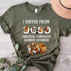 May include: Green t-shirt with the text "I suffer from OCD" with a graphic of squirrels forming the letters "OCD" and the text "Obsessive Compulsive Squirrel Disorder" below.