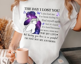 Op de afbeelding: Wit T-shirt met een paarse en zwarte galaxy-print en een knuffelend stel. De tekst luidt "De dag dat ik je verloor. Ik verloor ook mezelf. Ik probeer mezelf terug te vinden, maar het is moeilijk. Het is moeilijk omdat je een groot deel van mijn leven was. Je niet hier te hebben is zo pijnlijk. Ik ben gewoon niet meer mezelf."