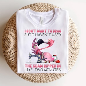 May include: White t-shirt with a pink flamingo holding a sewing machine and the text "I don't want to brag but I haven't used the seam ripper in like, two minutes."