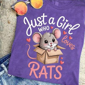 A purple t-shirt with a cartoon image of a mouse in a cardboard box, along with the text "Just a Girl who loves Rats" printed on it.