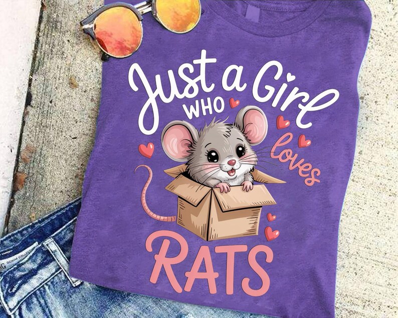 A purple t-shirt with a cartoon image of a mouse in a cardboard box, along with the text "Just a Girl who loves Rats" printed on it.