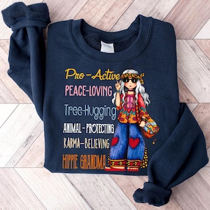 May include: Navy blue sweatshirt with a graphic of a hippie woman and the text "Pro-Active PEACE-LOVING Tree Hugging ANIMAL-PROTECTING KARMA-BELIEVING HIPPIE GRANDMA".