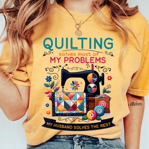 May include: Yellow t-shirt with a colorful sewing machine and a quilt design. The text reads "Quilting solves most of my problems. My husband solves the rest."