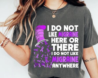 May include: A charcoal gray t-shirt featuring a graphic of a purple striped top hat and numerous small purple awareness ribbons. The text reads: I DO NOT LIKE MIGRAINE HERE OR THERE I DO NOT LIKE MIGRAINE ANYWHERE, with the word MIGRAINE in purple.