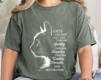 Può includere: Una maglietta verde con un contorno bianco della testa di un gatto e il testo "CATS ARE NOT JUST CATS THEY ARE Sanity THEY ARE Happiness THEY ARE Teachers Therapists AND BEST FRIENDS".