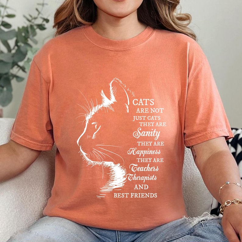 a woman sitting on a couch wearing a cat t - shirt