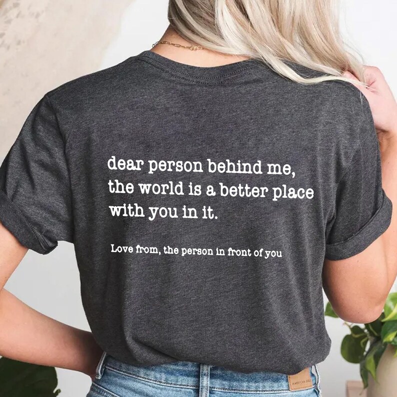 a woman wearing a t - shirt that says dear person behind me, the world