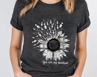 May include: A dark gray t-shirt with a white sunflower design. The sunflower is made up of bowling pins and a bowling ball in the center. The text "You are my sunshine" is printed below the sunflower.