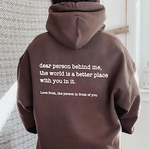 a person wearing a brown hoodie with a quote on it