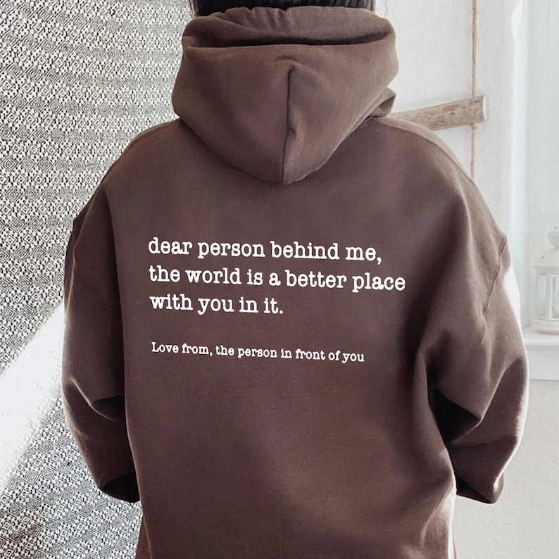 a person wearing a brown hoodie with a quote on it