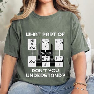 May include: A green t-shirt with a white graphic of a semi-truck transmission gear shift pattern. The text "WHAT PART OF" and "DON'T YOU UNDERSTAND?" is printed on the shirt.