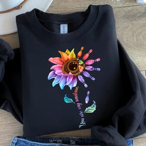 May include: Black sweatshirt with a rainbow sunflower design and the text "You are my sunshine" in a white font. The sunflower is made up of bowling pins.