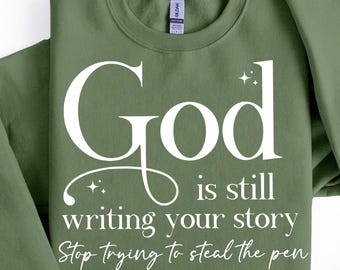 May include: A green sweatshirt with the text "God is still writing your story. Stop trying to steal the pen." in white.
