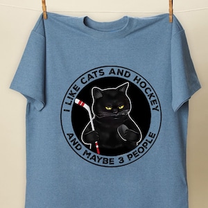 a blue t - shirt with a black cat holding a toothbrush