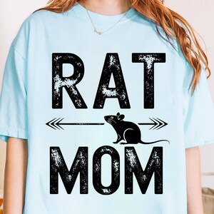 A person wearing a light blue t-shirt with the text "RAT MOM" printed on it.