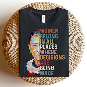 May include: A black t-shirt with a colorful portrait of Ruth Bader Ginsburg and the text "Women Belong In All Places Where Decisions Are Being Made".