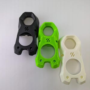 May include: Three 3D printed plastic cases in black, green, and white. Each case has a hexagonal shape with a circular opening in the center.