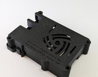 May include: Black plastic case with a fan cutout and a circular design in the centre. The case is designed to fit a Raspberry Pi.