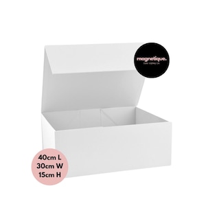 Op de afbeelding: Een witte kartonnen doos met een scharnierend deksel, open om het interieur te laten zien. De doos is 40 cm lang, 30 cm breed en 15 cm hoog. De doos is gelabeld met "magnetique. Ease Gifting Co."