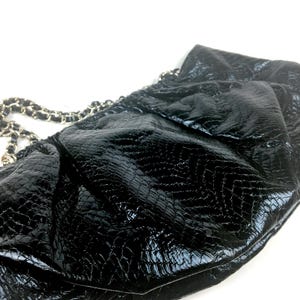 Puede incluir: Bolso de mano de cuero negro con correa de cadena y un dise&ntilde;o texturizado con estampado de cocodrilo.