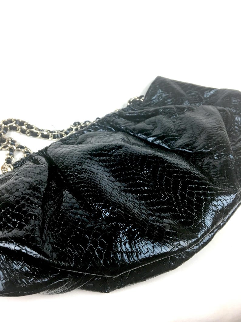 Puede incluir: Bolso de mano de cuero negro con correa de cadena y un dise&ntilde;o texturizado con estampado de cocodrilo.