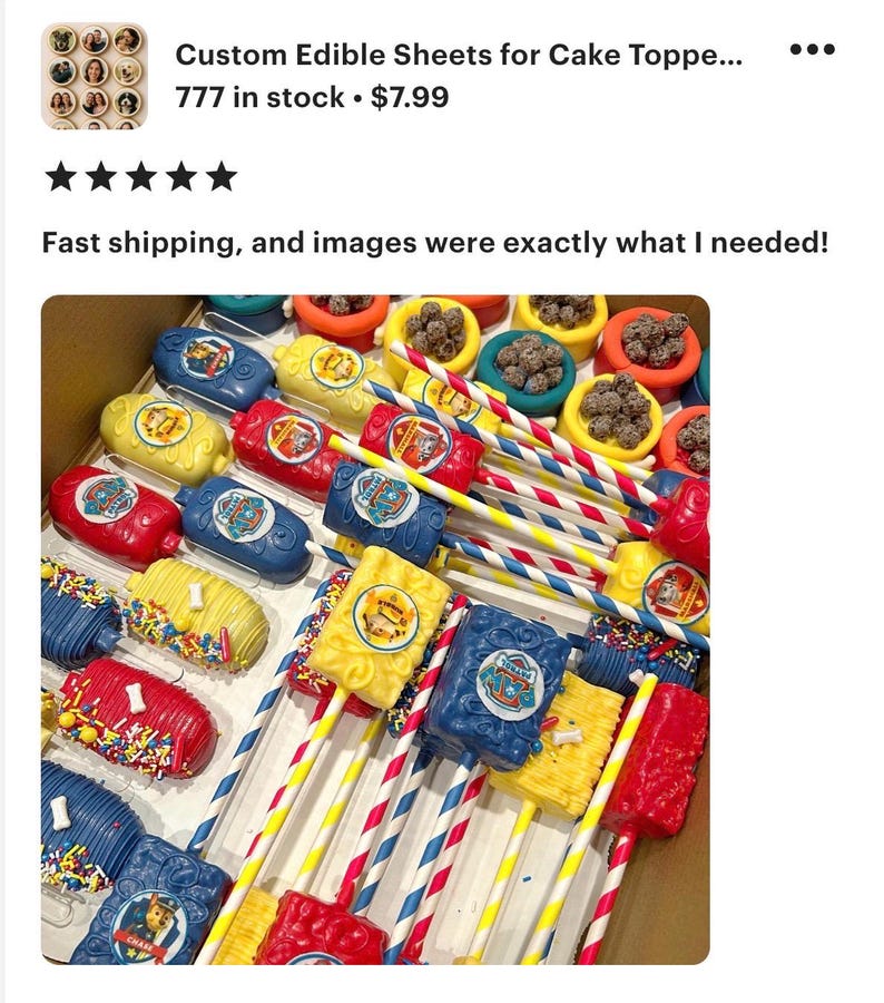 May include: A box filled with colorful edible cake toppers on sticks. The toppers are in various shapes and colors, including red, yellow, and blue, with character logos. The image also shows cake pops with sprinkles and colorful straws.