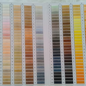 May include: A color chart displaying a wide range of thread colors. The chart is organized in columns, with each column showcasing a gradient of shades. Colors range from white and beige to various shades of brown, blue, and yellow.