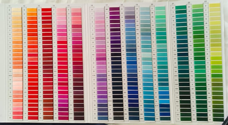 May include: A color chart displaying a wide array of thread colors. The chart is organized in vertical columns, showcasing shades of orange, red, pink, purple, blue, and green. Each color is represented by a series of thread samples.