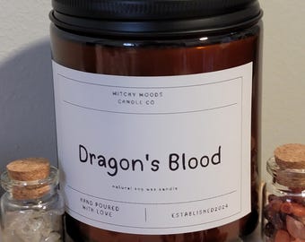 Può includere: Un barattolo di vetro marrone per candele con un coperchio nero. L'etichetta riporta "Witchy Woods Candle Co" e "Dragon's Blood natural soy wax candle". L'etichetta riporta anche "Hand Poured with Love" e "Established 2024".