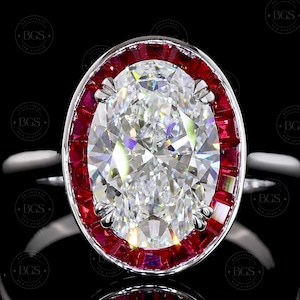 May include: An oval-cut clear gemstone ring featuring a halo of rectangular-cut red rubies set in a silver-toned metal band. The central stone is faceted and reflects light, surrounded by a continuous border of vibrant red stones in a prong setting.
