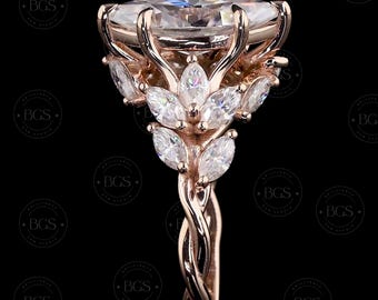 May include: A rose gold ring featuring a large oval-cut center stone held by prongs. The band and setting are adorned with multiple marquise-cut stones arranged in a leaf-like pattern, creating a detailed, branching structure around the center gem.